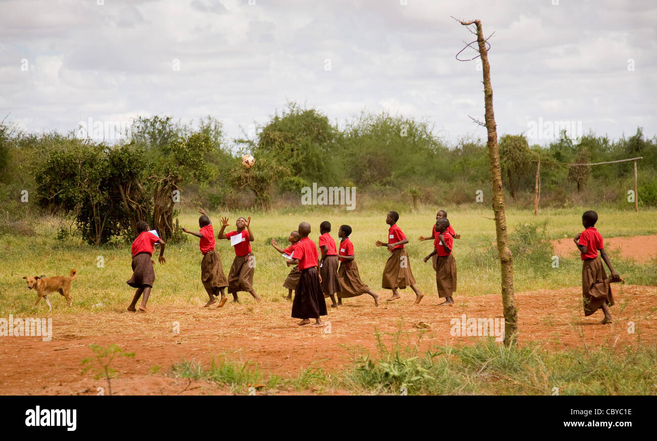 Enfants Adolescents jouant un jeu de rugby sur un terrain de jeu près de l'école dans le sud du Kenya Voi pendant que le chien regarde sur Banque D'Images