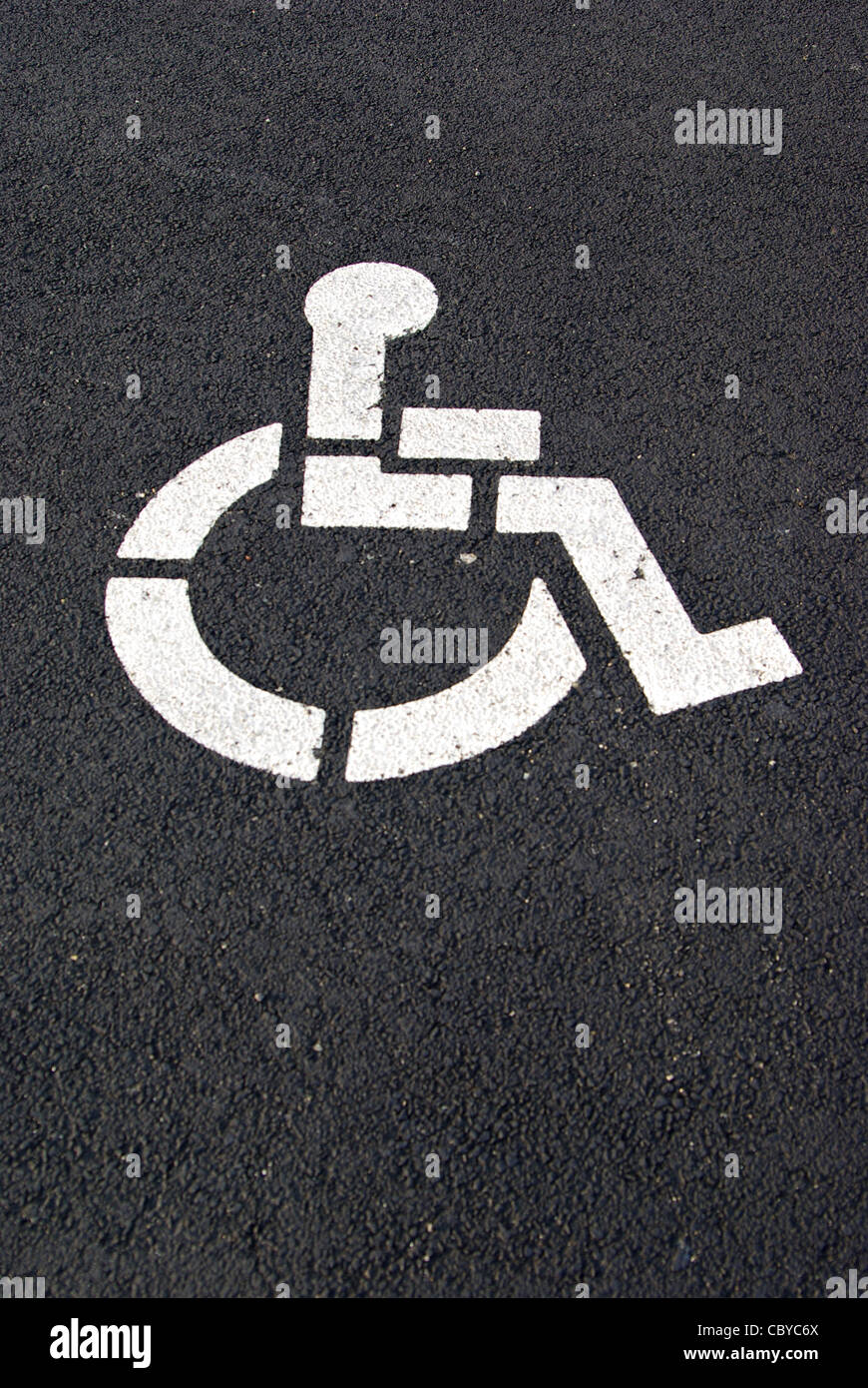 Un parking handicap blanc symbole est peint sur un revêtement noir. Banque D'Images