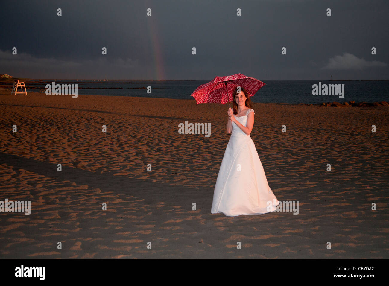 Photo d'une jeune mariée dans sa robe à la plage debout sous un