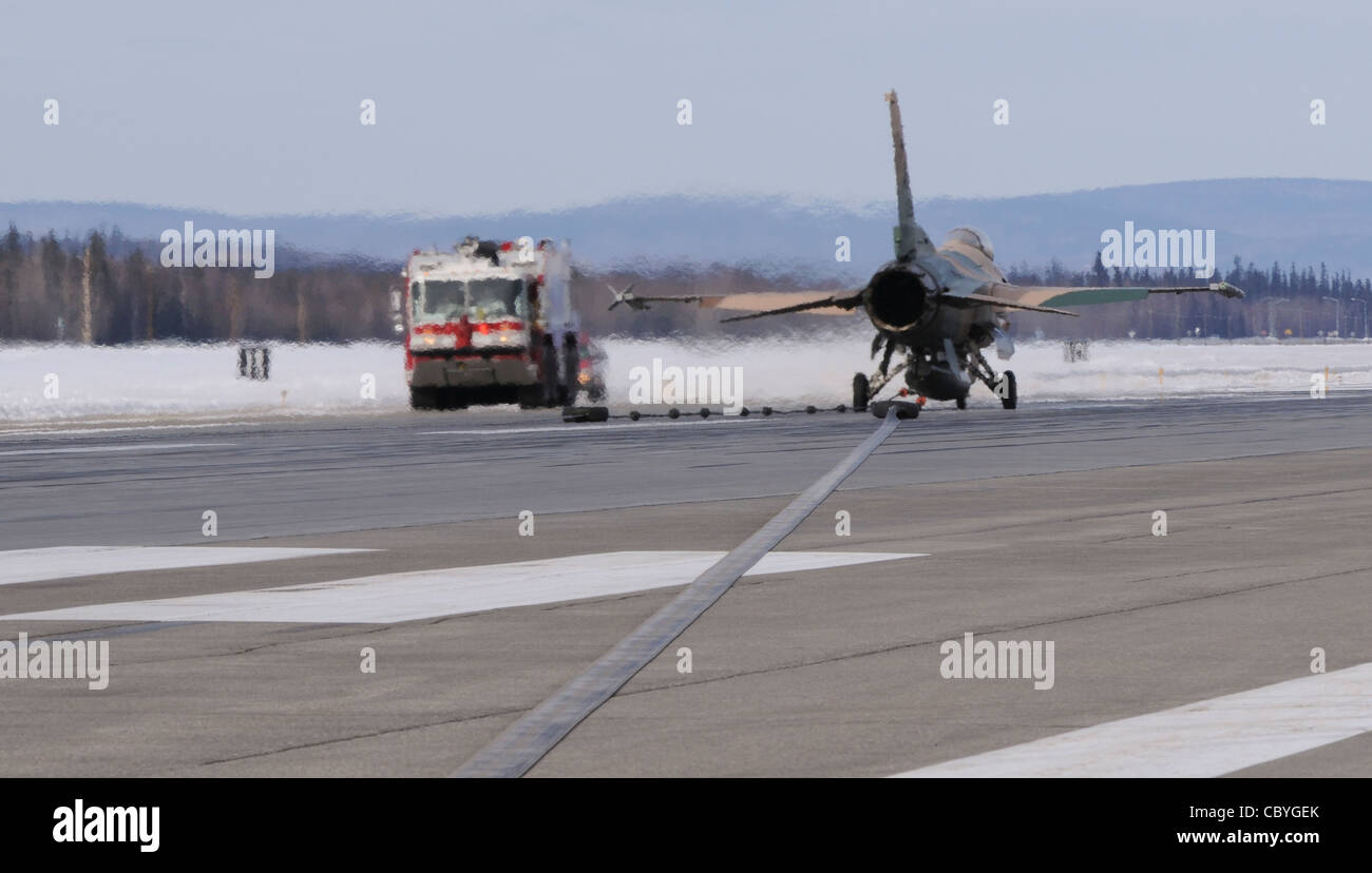 Un faucon de combat F-16, le 18e Escadron d'agresseurs, est assis sur la piste après avoir engagé un câble d'arrêt à une vitesse de 124 noeuds le 25 mars 2009, base aérienne d'Eielson, Alaska. Le câble est semblable à celui utilisé sur les porte-avions de la Marine et doit être certifié une fois par an pour assurer un fonctionnement correct en cas d'urgence. Banque D'Images