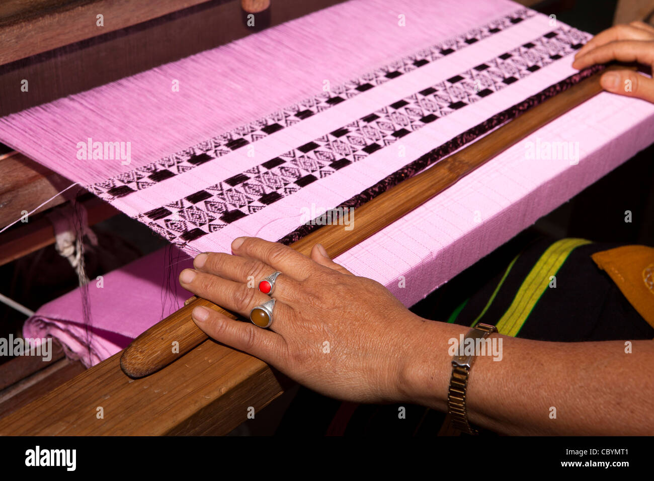 L'Inde, de l'Arunachal Pradesh, le long, Paya village, mains de femme à part loom weaving tissu rose Banque D'Images