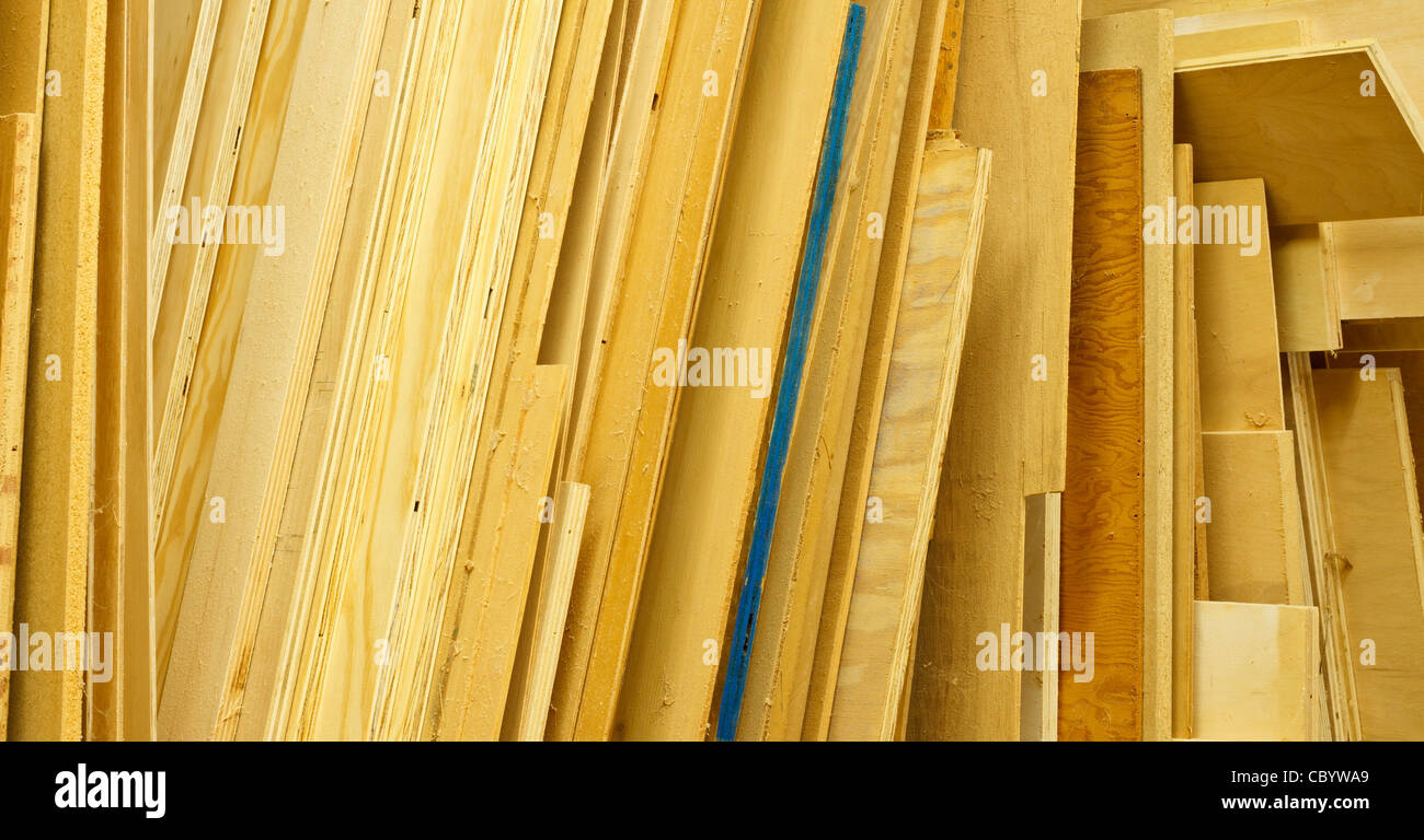 Feuilles de divers types de contreplaqué sont empilées dans un atelier de travailleurs du bois. La sciure et les araignées sur les surfaces sont trouvés près. Banque D'Images