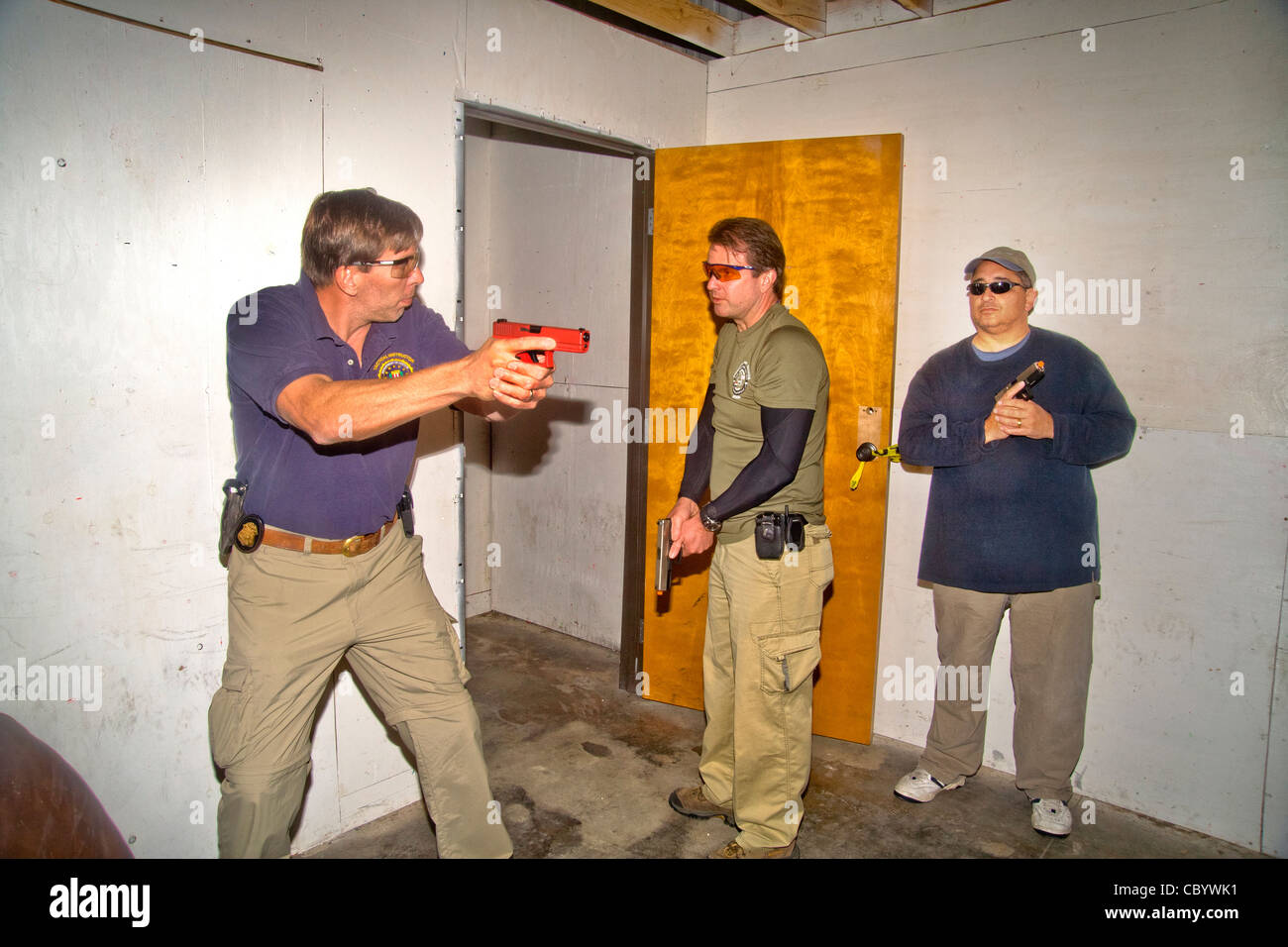 Sous l'oeil d'un instructeur, les agents d'application de la pratique d'entrer ou 'violer' une chambre avec des armes. Banque D'Images