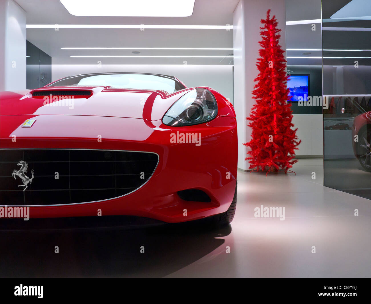 Ferrari rouge 'California' sur l'affichage de voiture de sport en vente en salle d'exposition avec l'arbre de Noël rouge derrière Banque D'Images