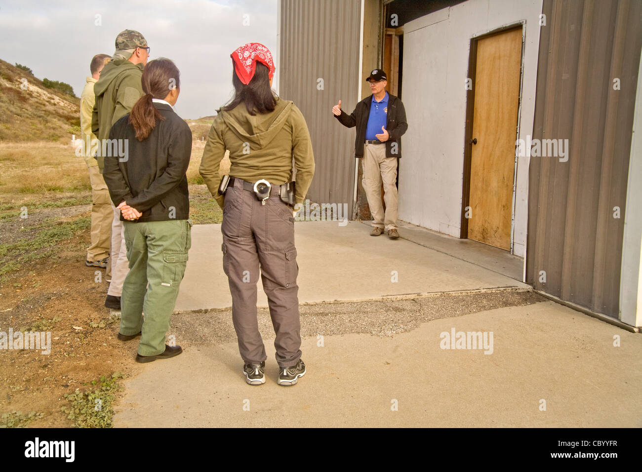 Une équipe d'agents d'application de la loi reçoivent des instructions sur les méthodes d'entrée ou 'violer' une chambre avec des armes à l'établissement de formation Banque D'Images