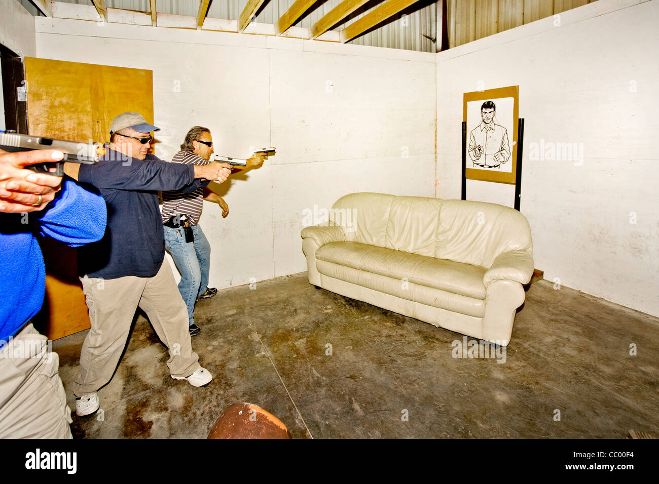 Sous l'oeil d'un instructeur, les agents d'application de la pratique d'entrer ou 'violer' une chambre avec des armes. Banque D'Images