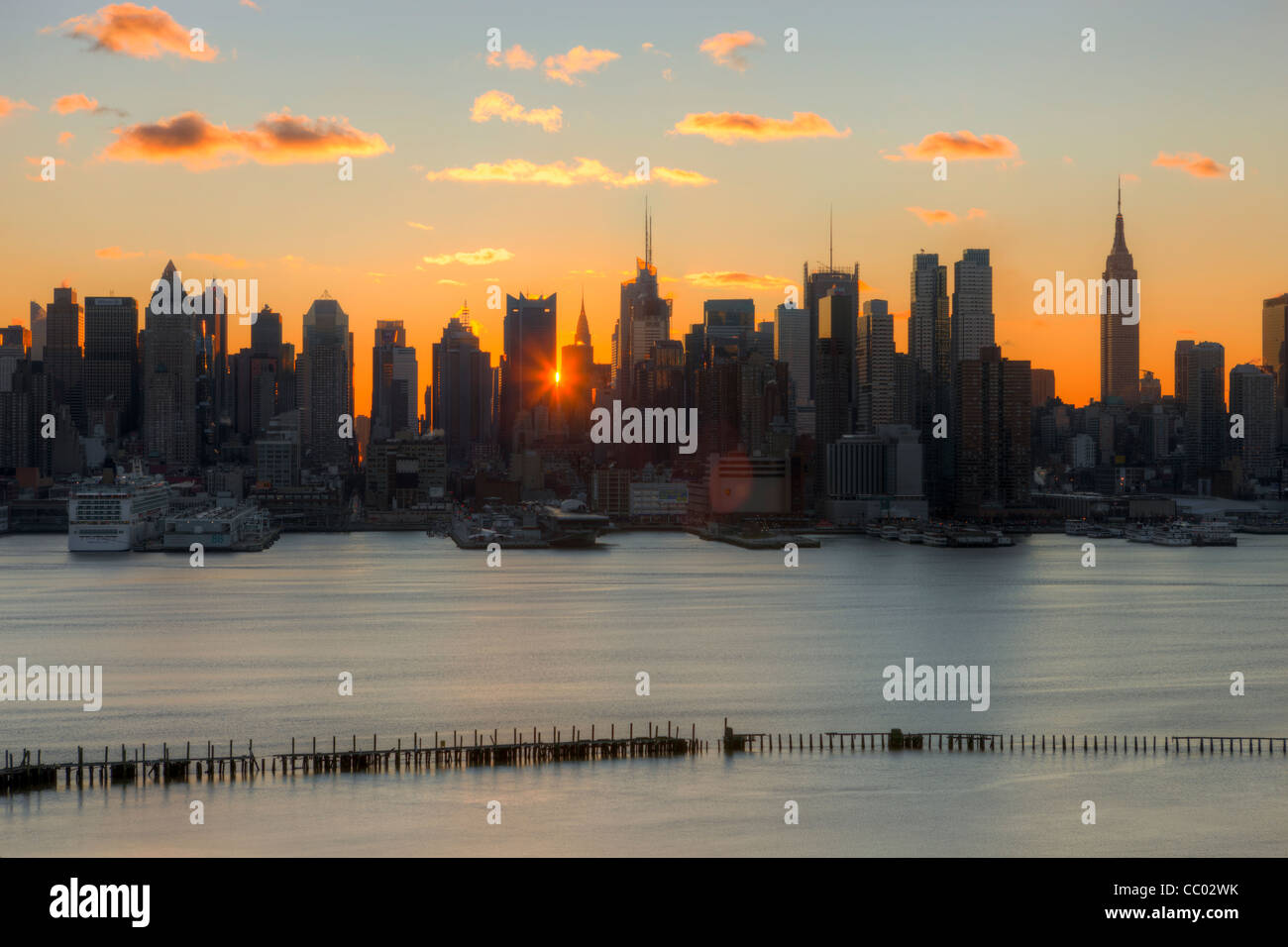 Le soleil brille à travers les bâtiments de la Mid-town Manhattan skyline au lever du soleil comme vu dans le New Jersey. Banque D'Images