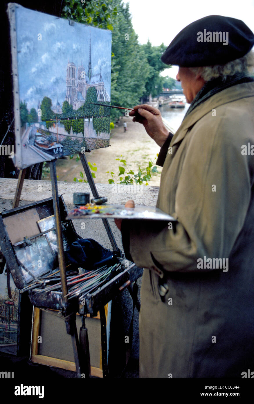 Un vieux peintre parisien travaille à l'extérieur sur son oeuvre dans le secteur de la célèbre cathédrale Notre-Dame et la Seine à Paris, France. Banque D'Images