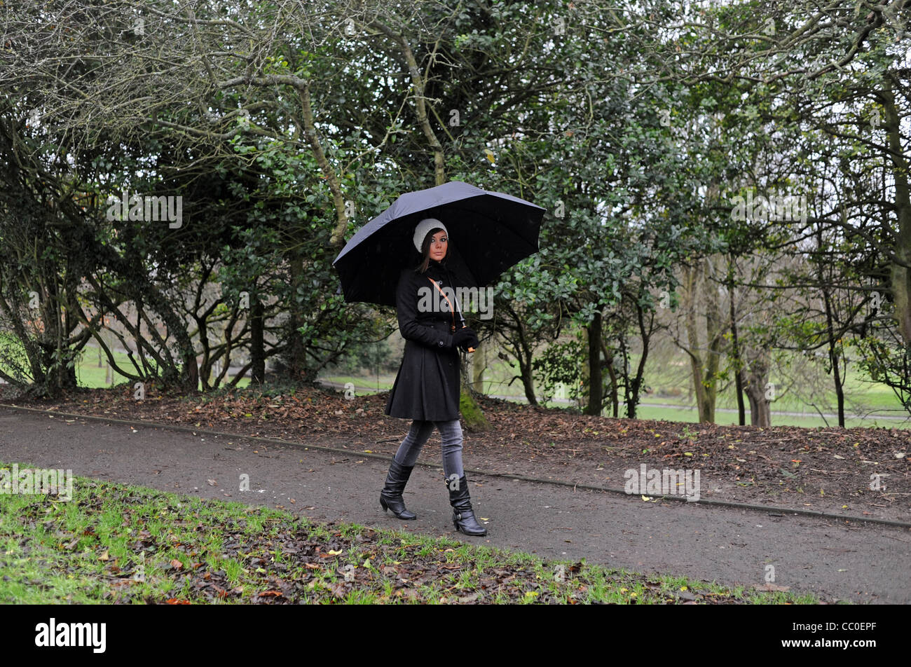 Jeune femme avec un grand parapluie noir dans un parc Brighton par temps humide, UK Banque D'Images