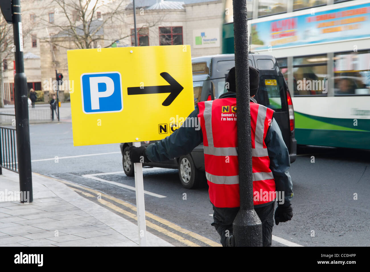 Homme avec placard montrant les indications pour le parking NCP à Newcastle upon Tyne à Noël Banque D'Images