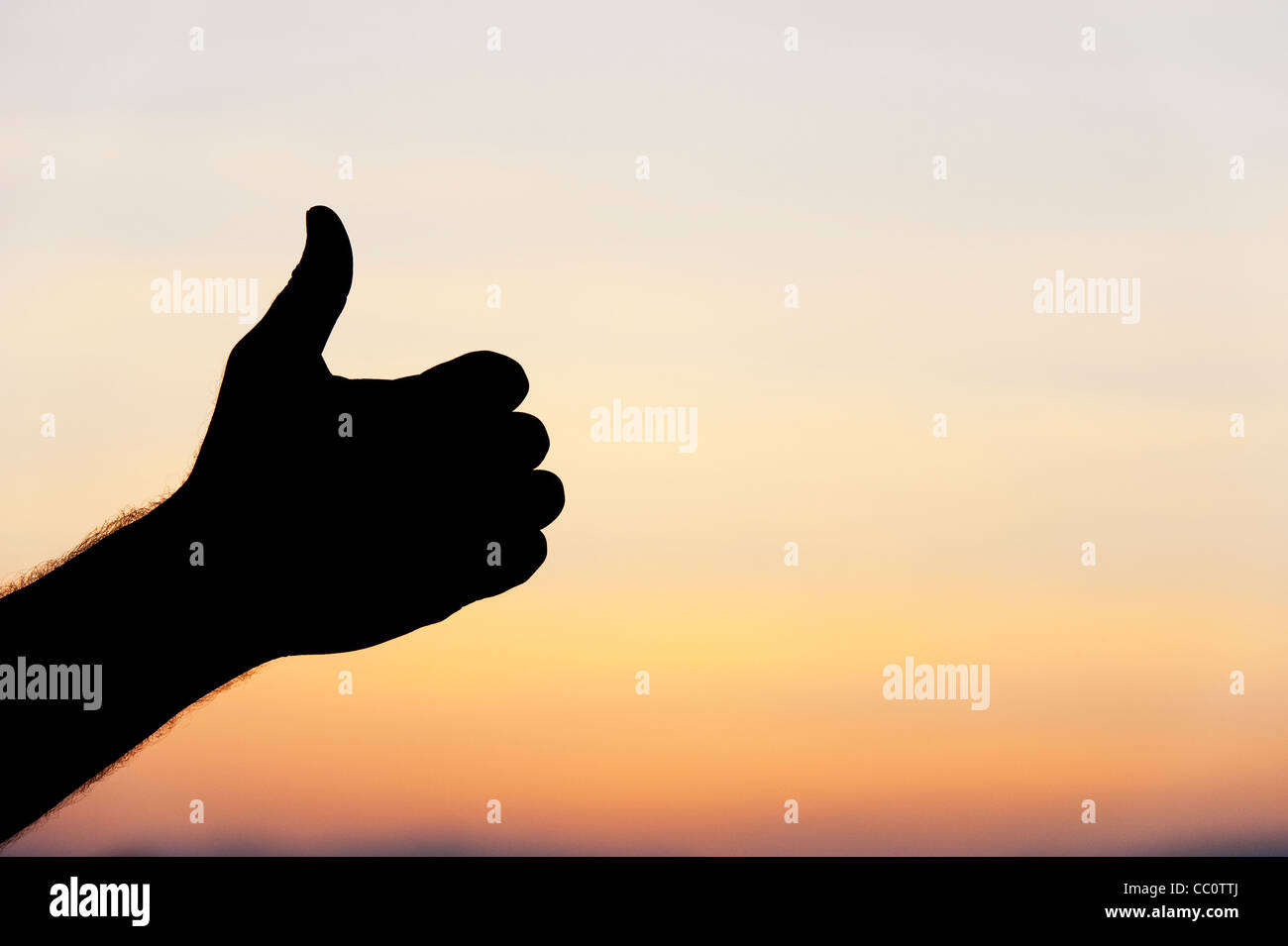 Thumbs up silhouette main contre l'aube sky Banque D'Images