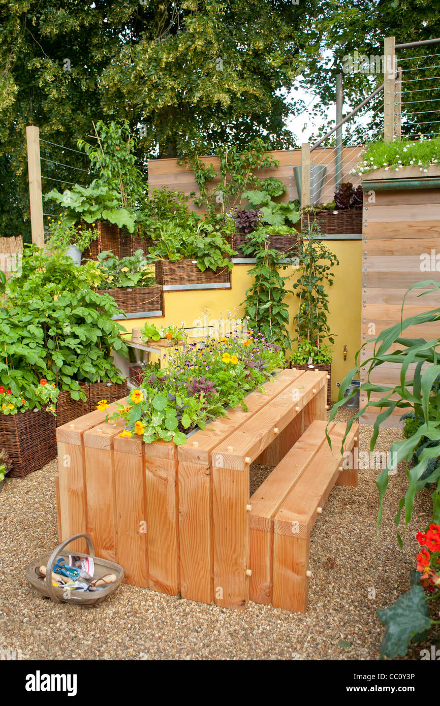 Table et bancs en bois dans la cour intérieure avec jardin cuisine cueillies et de fleurs en centre de table. Banque D'Images