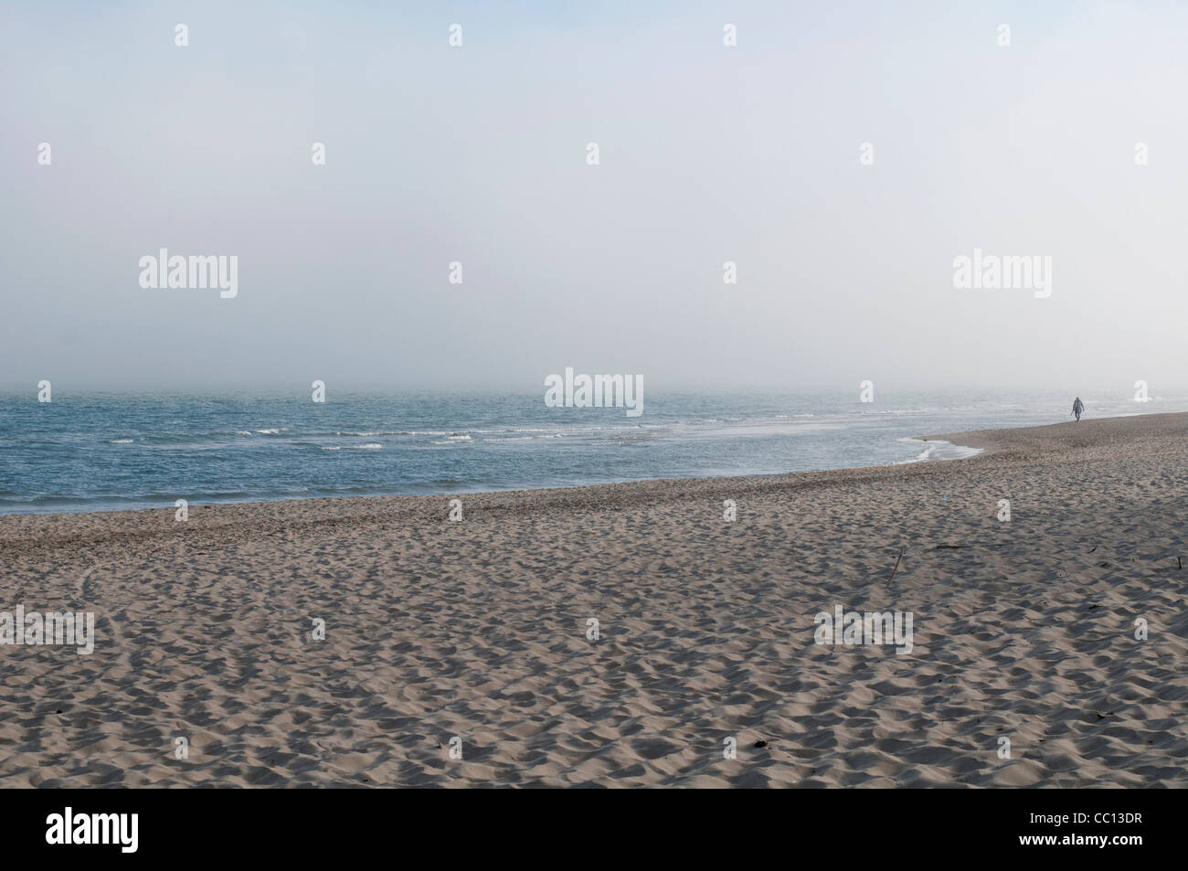 Brouillard d'entrants à partir de la mer à Vias, dans le sud de la France, figure masculine (plus de 50 ans) le port de bonnet rouge promenades le long de la côte. Banque D'Images