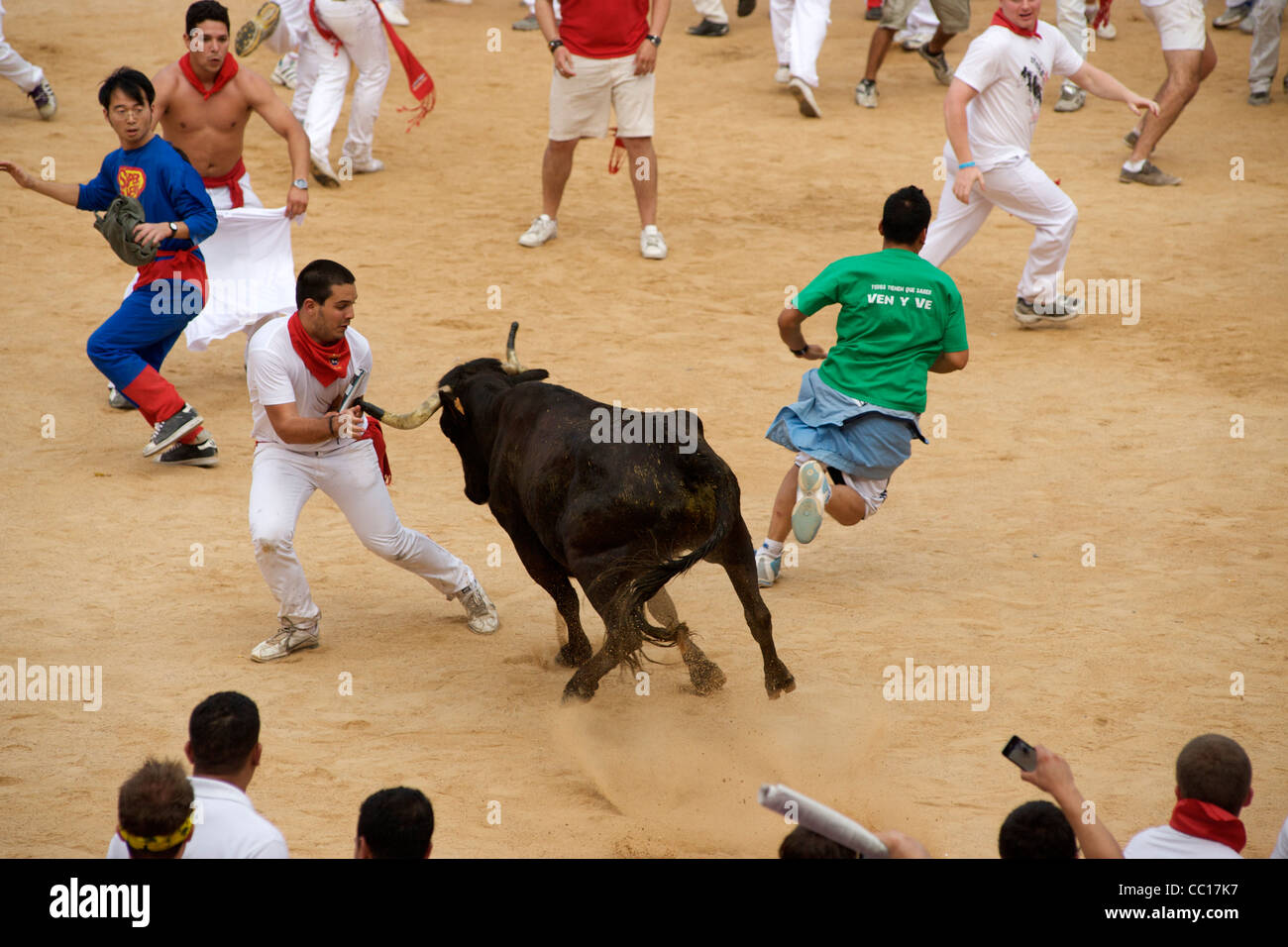 Les personnes en cours d'exécution d'une vache dans la fête à la suite de la matinée bull run au festival de San Fermin à Pampelune, Espagne. Banque D'Images