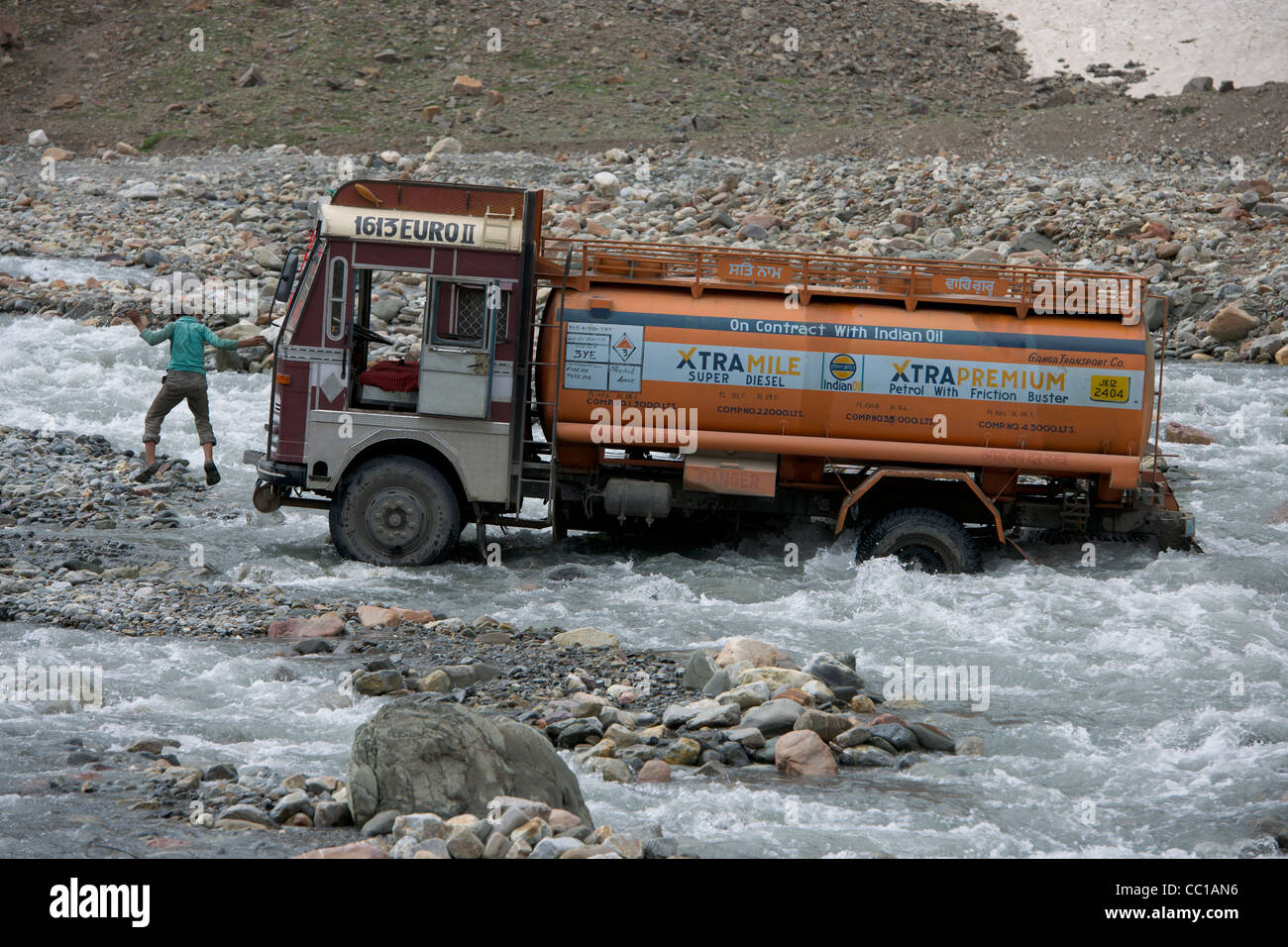 Chauffeur de camion-citerne de la cabine d'un saut d'brin tandis qu'une rivière à gué sur la route Leh-Manali, Himachal Pradesh, Inde Banque D'Images