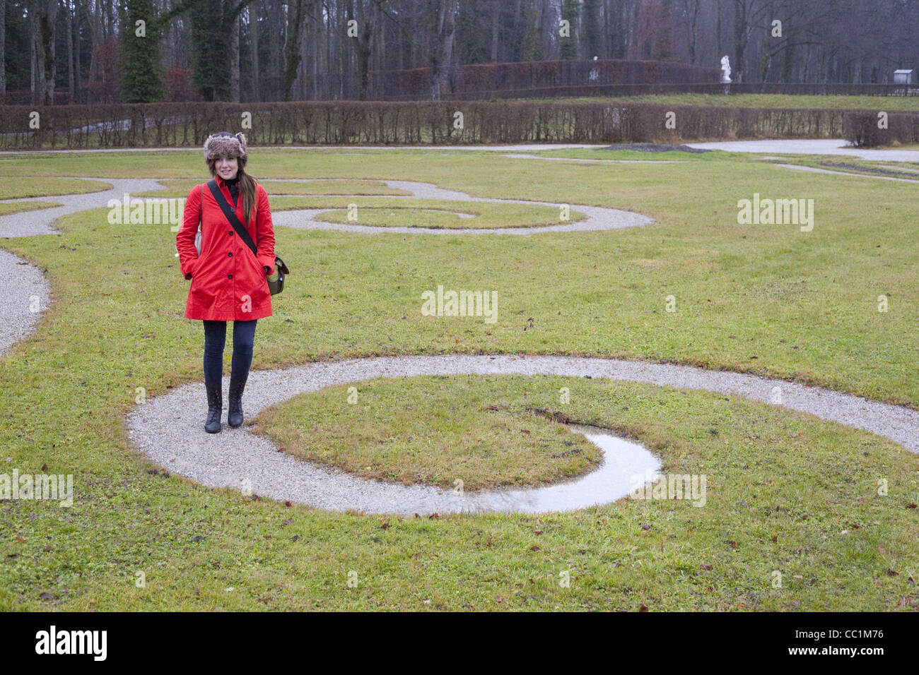 Une fille avec une veste rouge marche une trajectoire en spirale dans un jardin verdoyant à l'Herreninsel palace construit par le roi Louis II. Banque D'Images