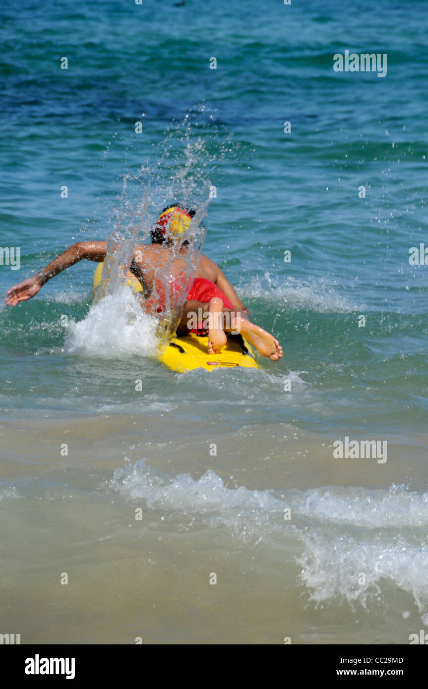 Un jeune maître nageur entre en action avec son surf pour sauver un nageur à Bondi Beach, Sydney, Australie Banque D'Images