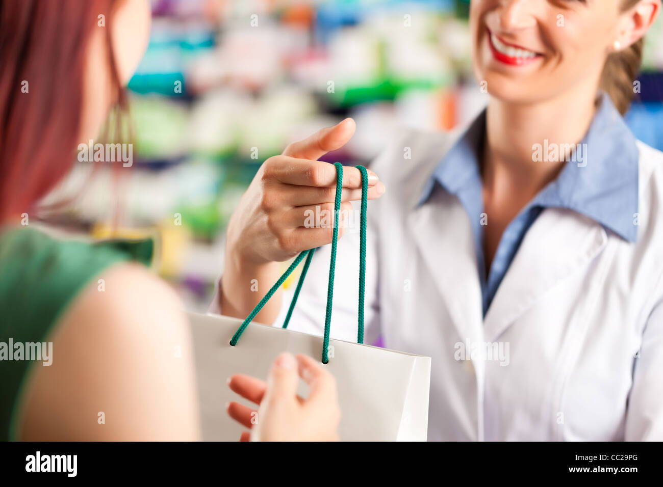 Pharmacien femelle avec un client de sexe féminin dans sa pharmacie Banque D'Images