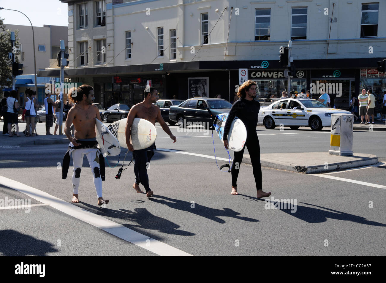 Trois jeunes hommes portant leurs planches de surf sur Campbell Parade à la plage de Bondi Beach, près de Sydney, Australie Banque D'Images