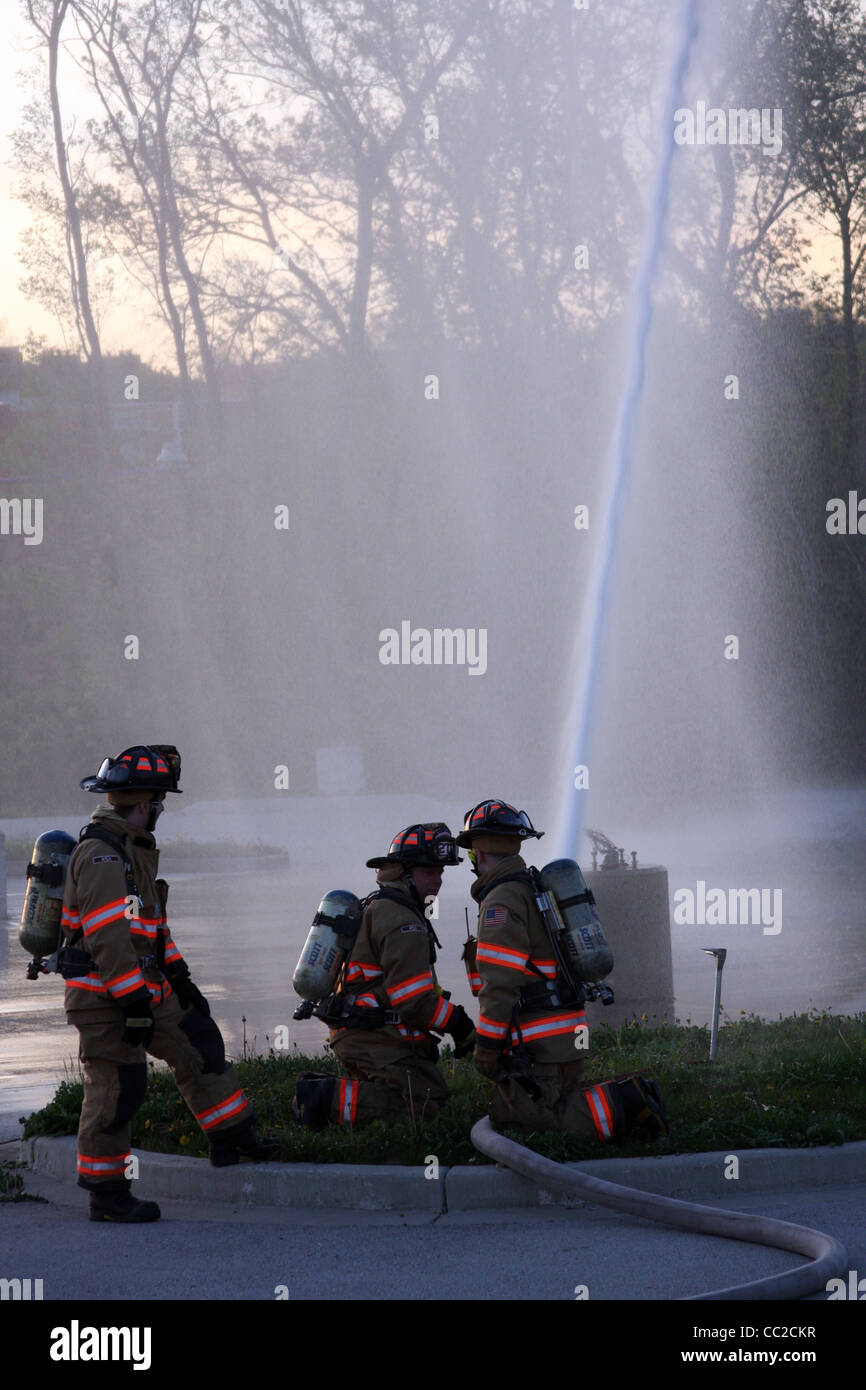 Trois pompiers de la commande d'un hoseline Banque D'Images