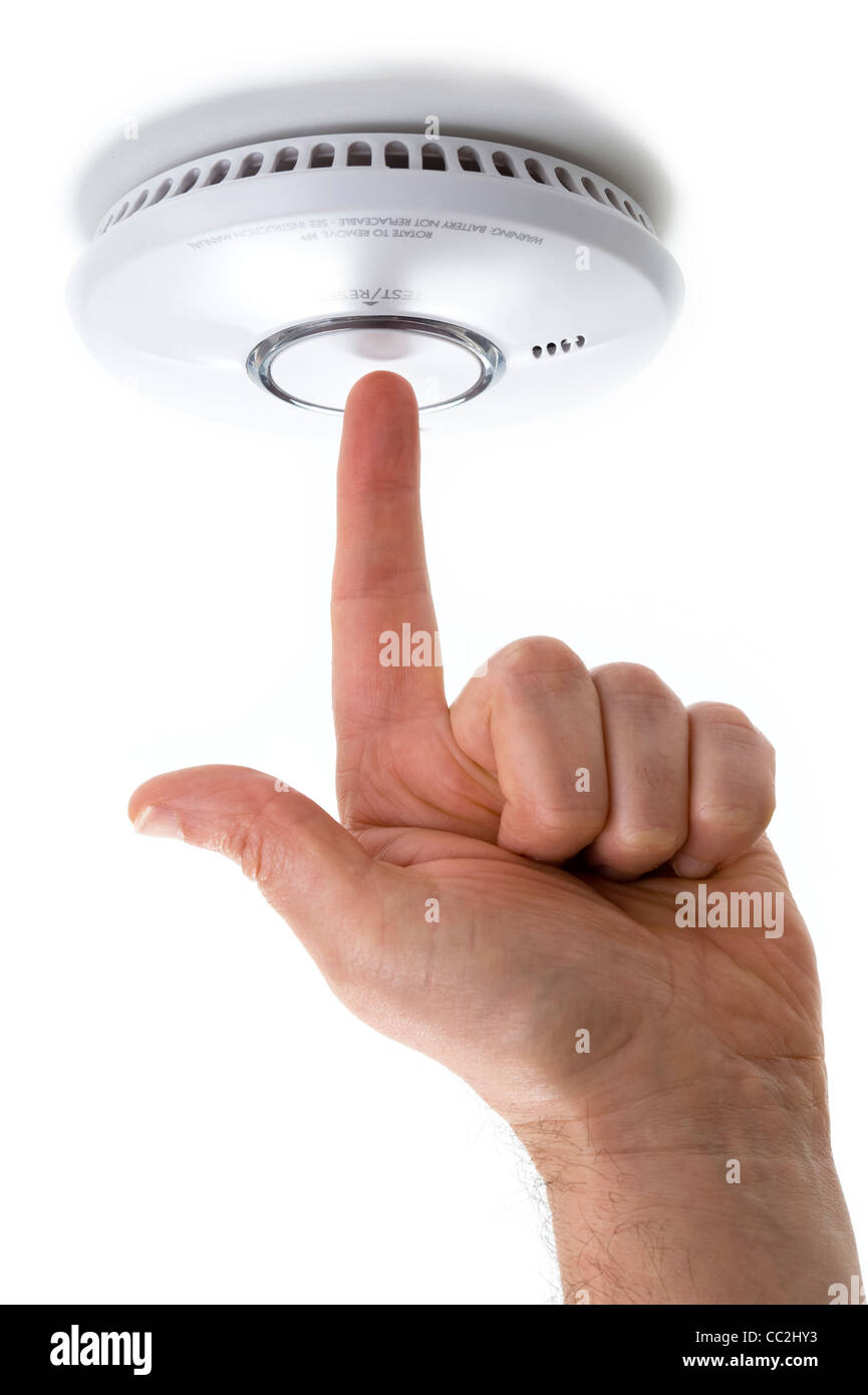 La main avec un doigt pointé l'essai d'un incendie domestique / détecteur de fumée isolé sur fond blanc Banque D'Images