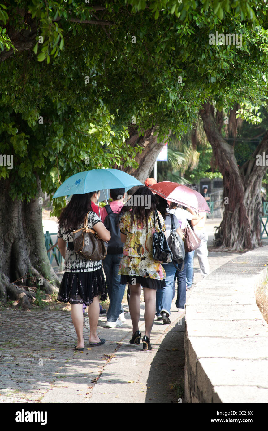 Les touristes avec l'aide de parasols parasols en marchant le long de l'Avenida da Republica de Macao Chine Banque D'Images