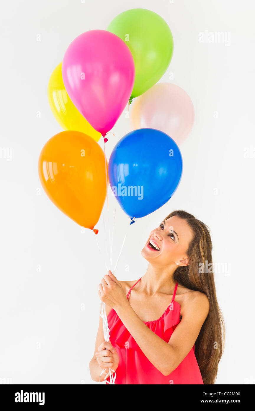 Smiling woman holding balloons, studio shot Banque D'Images