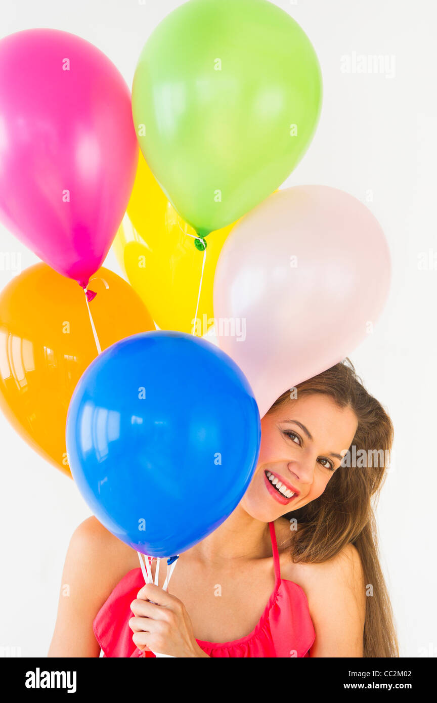 Smiling woman holding balloons, studio shot Banque D'Images