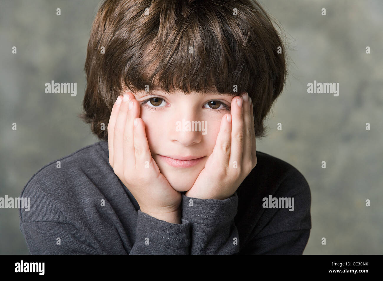 Portrait of boy (6-7) de la face dans les mains, studio shot Banque D'Images