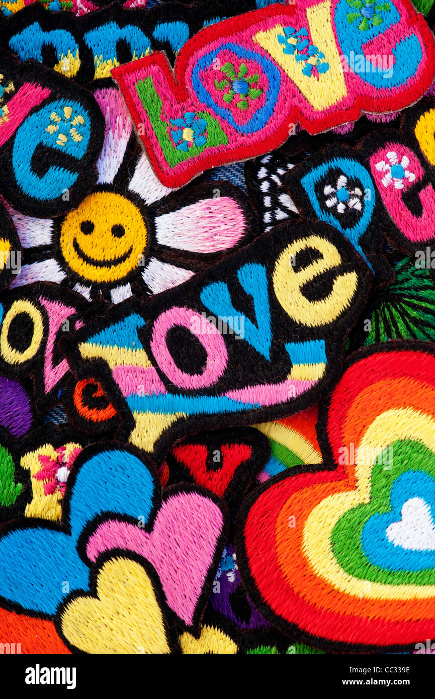 Fer à repasser la broderie sur des parcelles d'amour, de paix, multicolore mots heureux avec des coeurs sur fond noir Banque D'Images