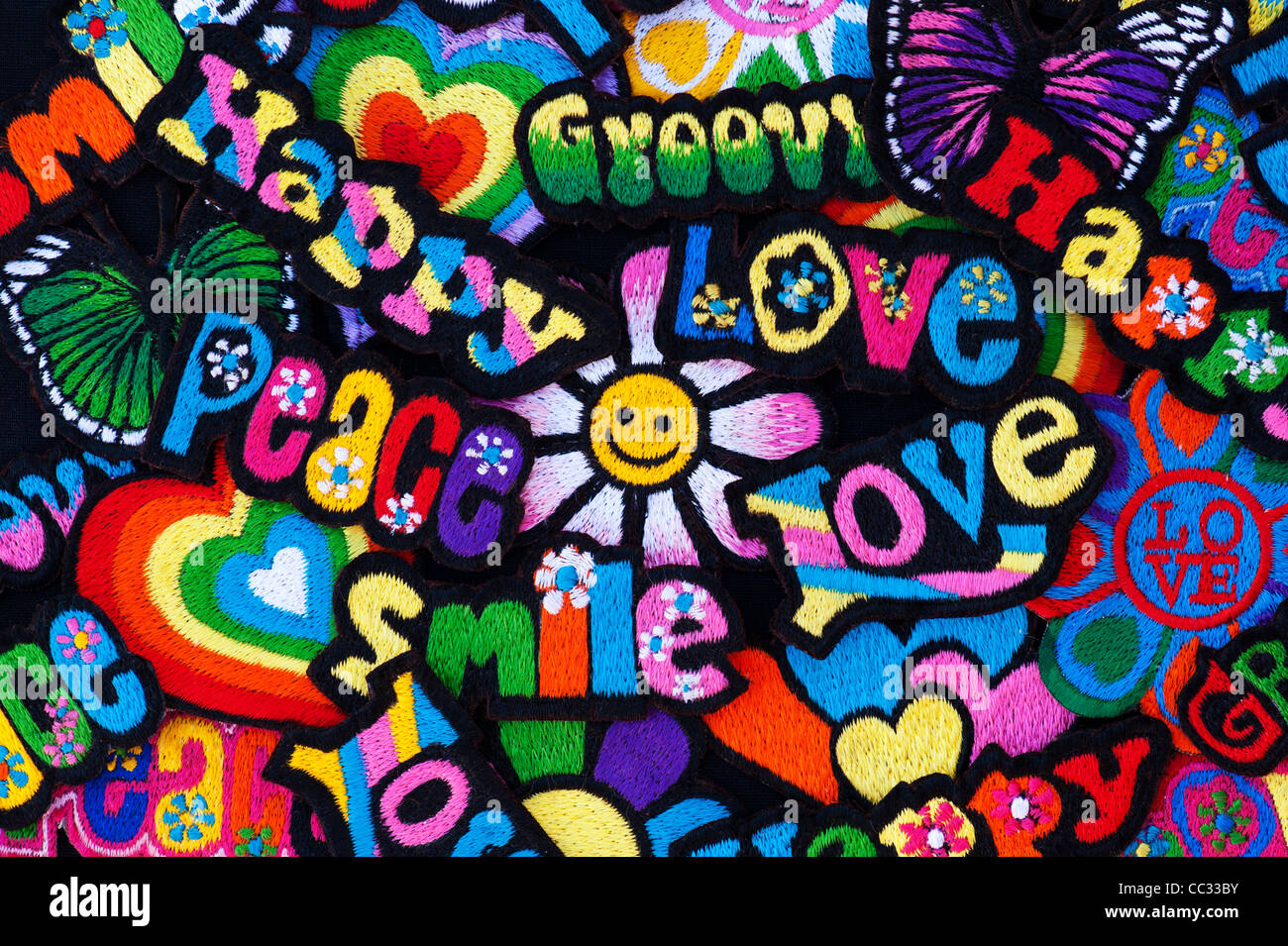 Fer à repasser la broderie sur des parcelles d'amour, de paix, de multicolores heureux, sourire, joie, Groovy mots avec une fleur sur fond noir Banque D'Images