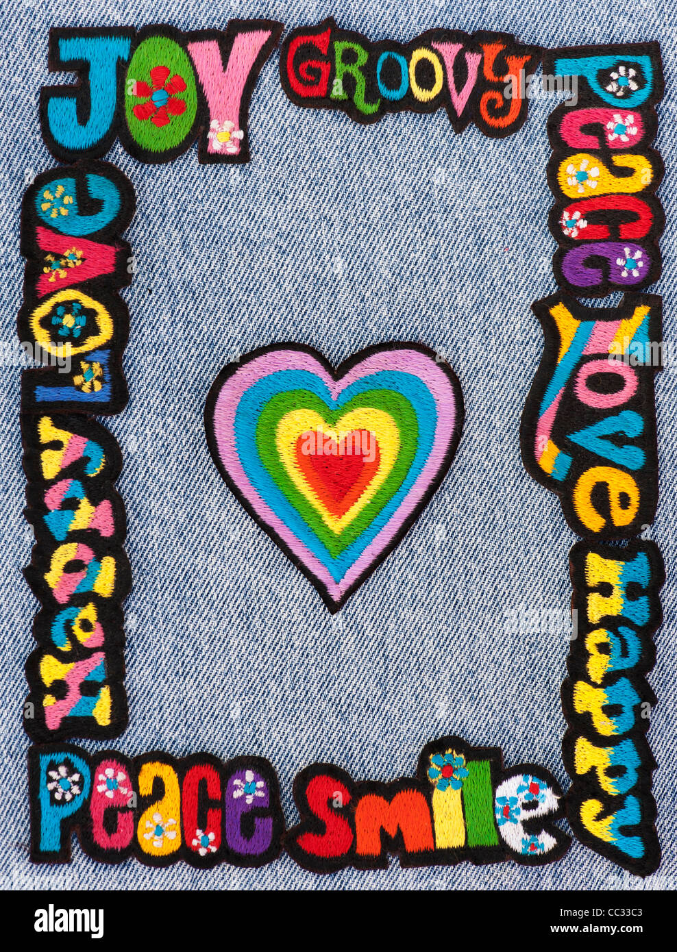 Fer à repasser la broderie sur des parcelles d'amour, de paix, multicolore mots heureux avec des coeurs sur un fond jean denim Banque D'Images