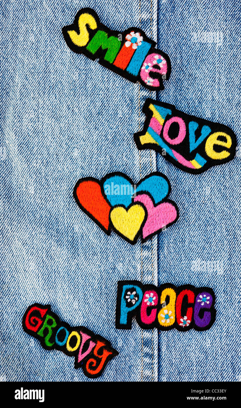 Fer à repasser la broderie sur des parcelles d'amour, de la paix et de multicolore mots sourire avec des coeurs sur un fond jean denim Banque D'Images