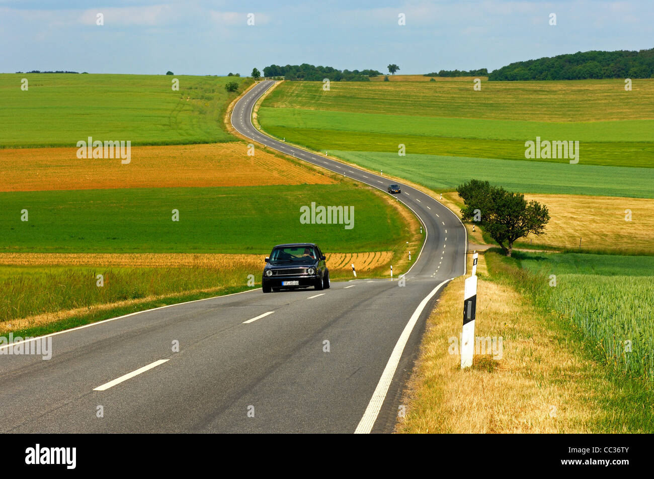 Route de campagne serpentant à travers champs dans un paysage vallonné, Rhénanie-Palatinat, Allemagne Banque D'Images