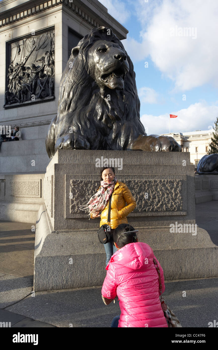 Femme d'origine asiatique touristes prenant des photos des lions à Trafalgar Square London England uk united kingdom Banque D'Images