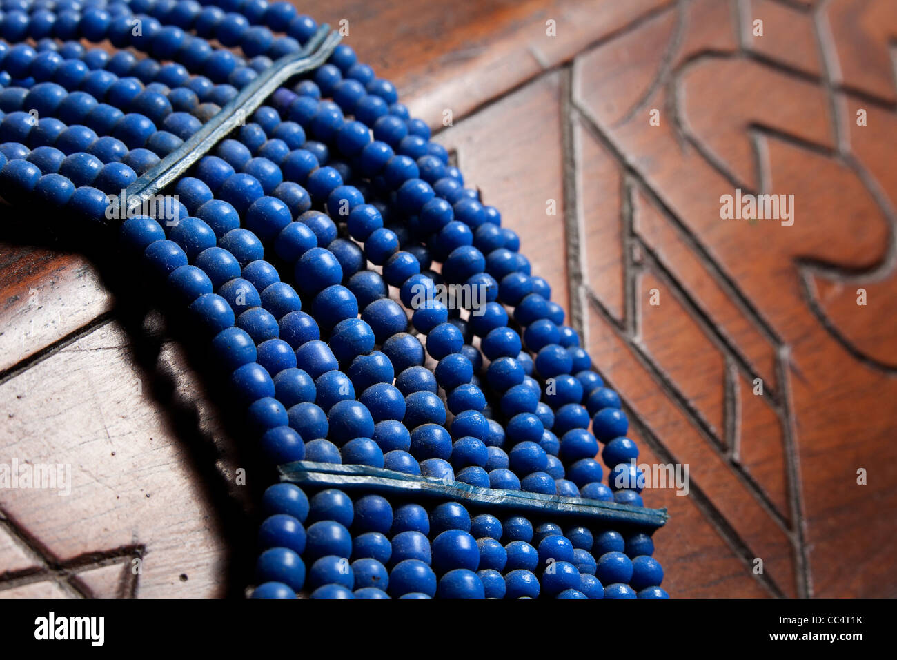 Collier de perles bleu tribal africain placé sur des meubles en arrière-plan. autochtones traditionnelles de l'artisanat local. Banque D'Images