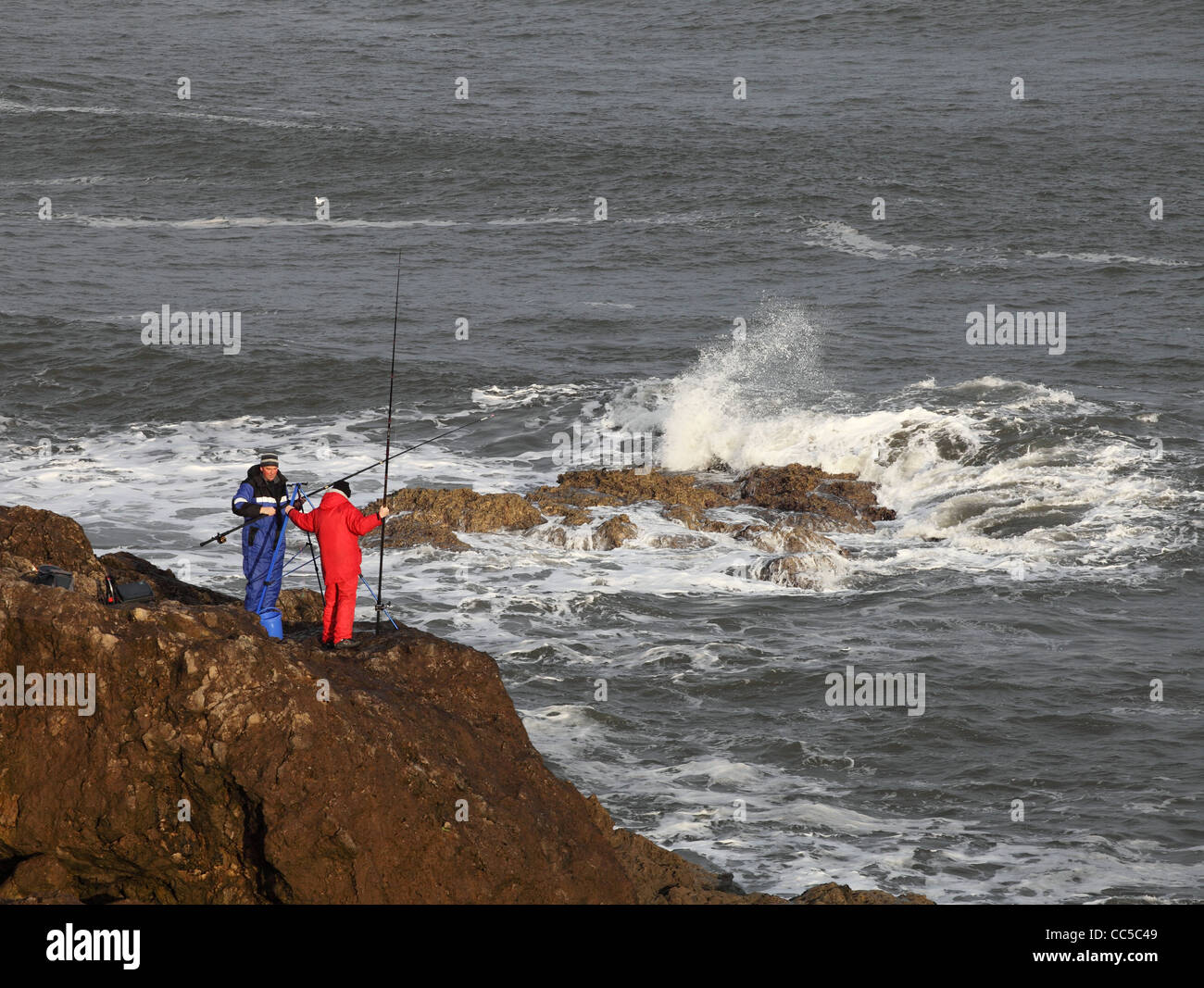 Deux hommes la pêche au large de la ligne de falaises sur la côte de la mer du nord près de South Shields, North East England UK Banque D'Images