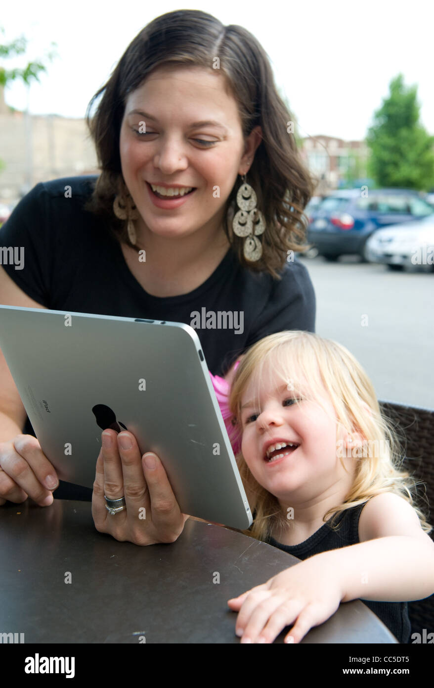 Portrait mère et fille interagir avec Apple iPad ensemble à la terrasse d'un café Banque D'Images