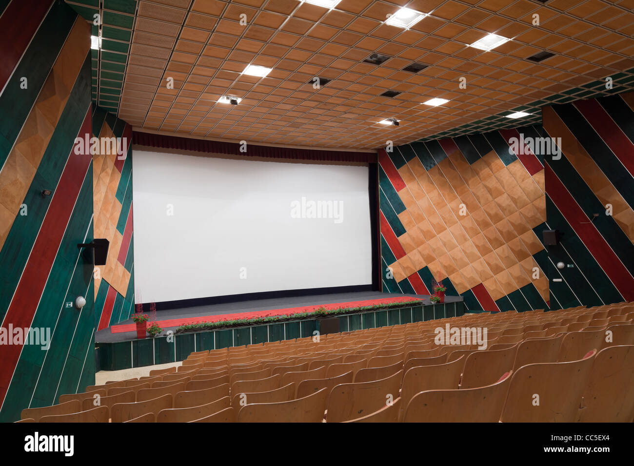 Salle de cinéma vide avec la ligne de chaises et écran de projection. Prêt pour l'ajout de votre propre photo. Vue de côté. Banque D'Images