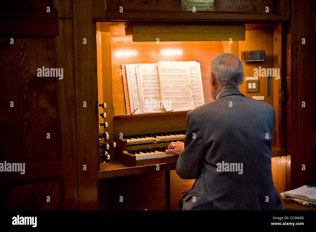 Vue arrière d'un homme caucasien âgé jouant l'orgue dans une église britannique. Banque D'Images