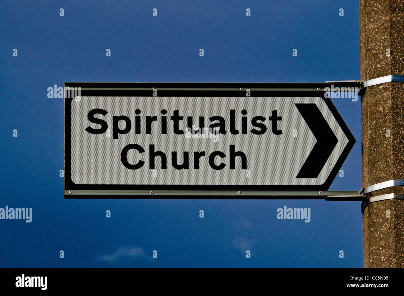 Panneau de l'église spiritualiste attaché à un poteau de lampe en béton, vu contre un ciel bleu clair. Banque D'Images
