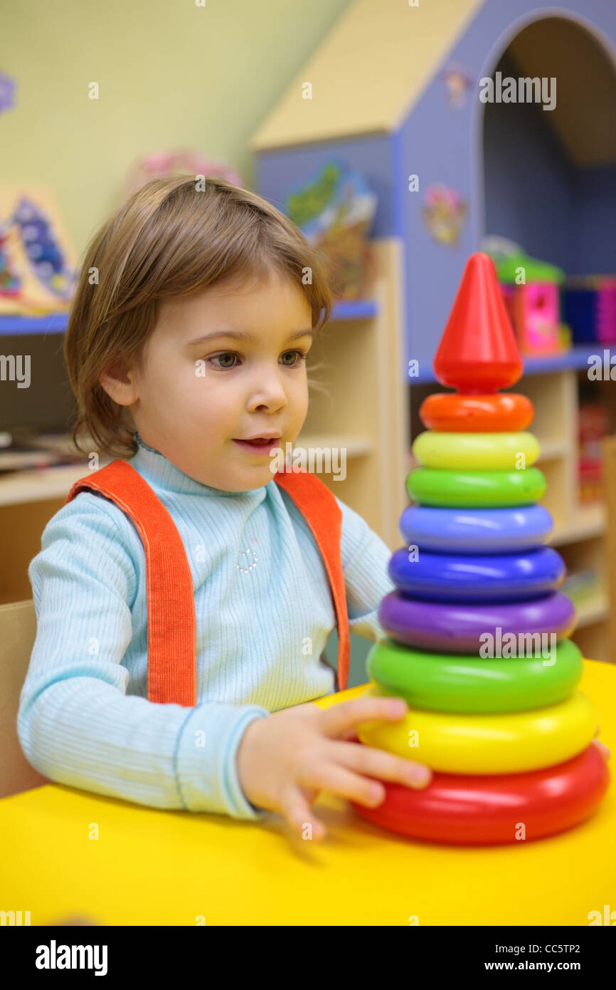 Petite fille joue dans l'école maternelle avec pyramide en plastique Banque D'Images