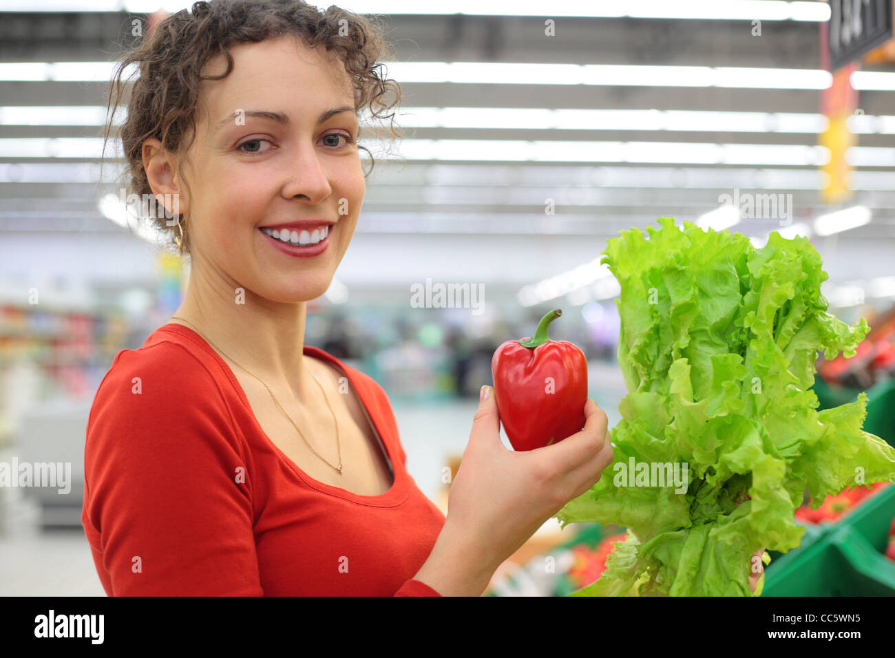 Jeune femme en boutique avec poivron rouge et salade Banque D'Images