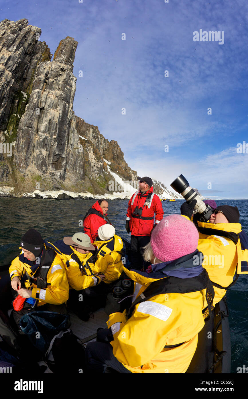 Les touristes en croisière en zodiac aventure arctique jeux gonflables, des falaises Alkefjellet colonie d'oiseaux de mer en été, Spitzberg, Svalbard Banque D'Images