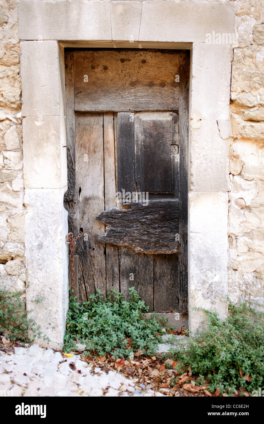 Une vieille porte en bois se trouve à l'intérieur d'un bâti en pierre sur un immeuble situé à Ménerbes, France Banque D'Images