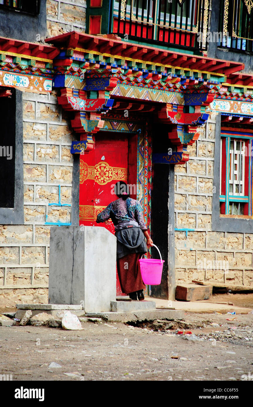 Femme tibétaine portant un seau d'eau dans sa maison, Lhassa, Tibet, Chine Banque D'Images