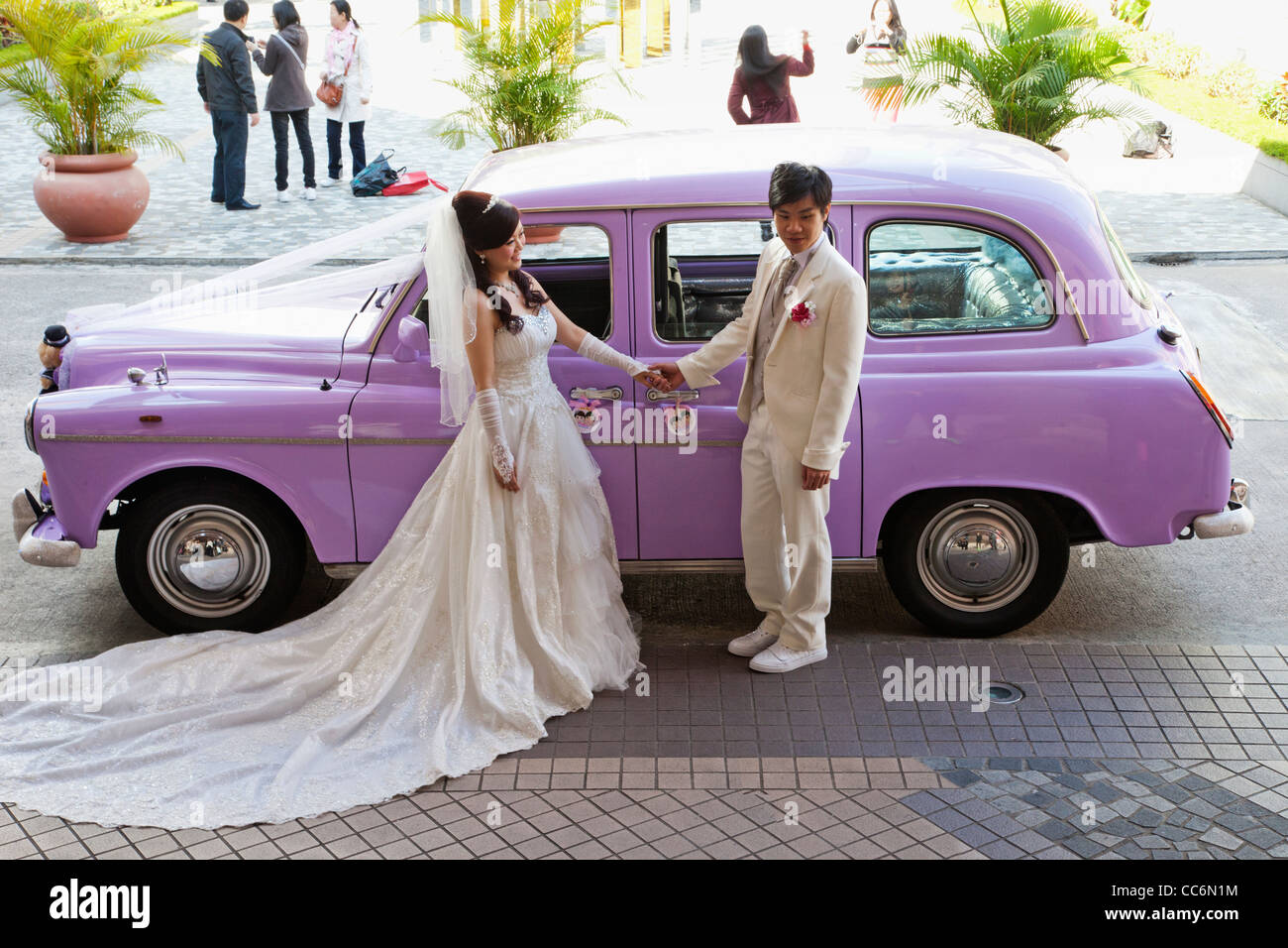 La Chine, Hong Kong, Wedding Couple posing in front of Pink London Taxi Cab Banque D'Images