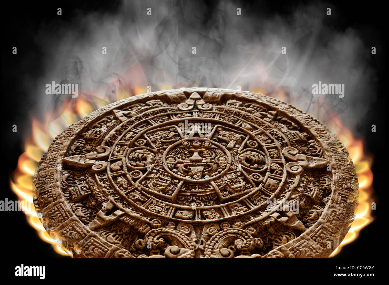 Calendrier maya apocalyptique sur le feu avec la fumée s'élevant de sa surface sur un fond noir Banque D'Images