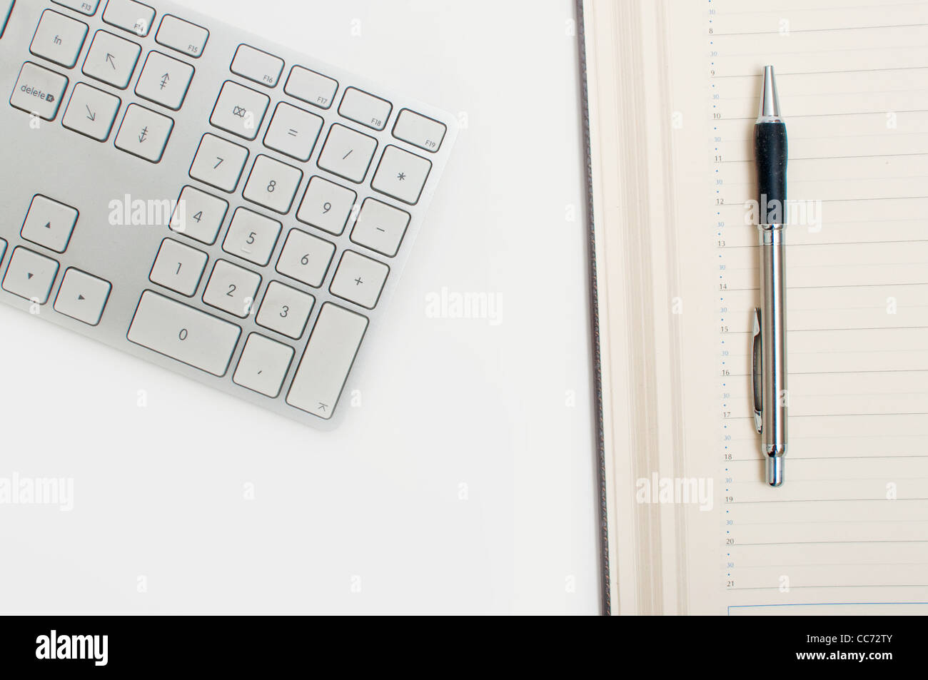 Détail de bureau, un clavier d'ordinateur, de l'ordre du jour et d'un stylo sur une table blanche. Concept d'entreprise. Banque D'Images