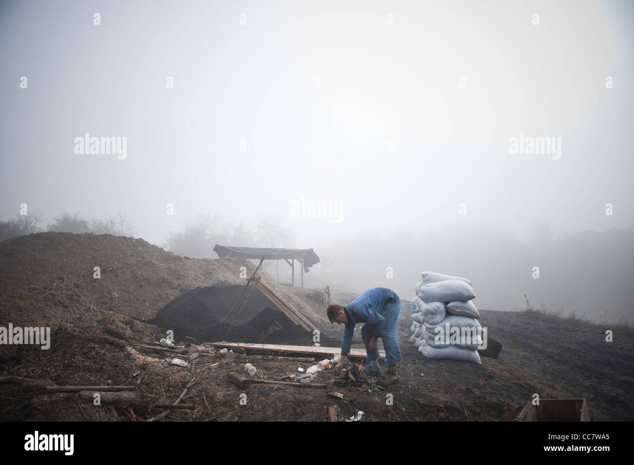 Un mineur de charbon illégale incendie préparation du café en face de la mine de charbon illégale à la périphérie de la ville de Zenica, en Bosnie centrale. Banque D'Images
